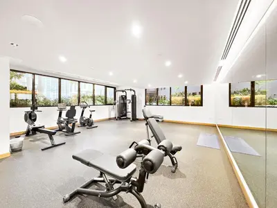 a gym with treadmills and ellipticals in a room with windows at FIRST CLASS Studio Modern Elegance in Dubai
