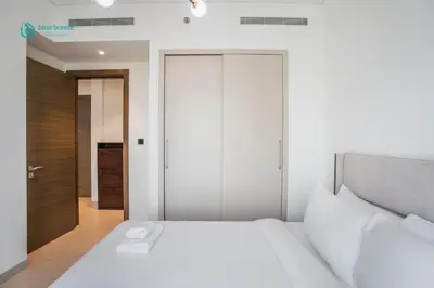 a bedroom with a white bed and a closet at Blue Breeze - 2 Bedroom near Downtown, Elegant Retreat in Sobha in Dubai