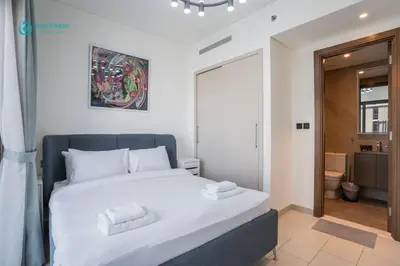 a bedroom with a large bed and a bathroom at Blue Breeze - 2 Bedroom near Downtown, Elegant Retreat in Sobha in Dubai