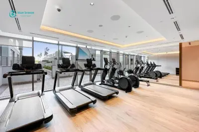 a gym with a row of treadms and elliptical machines at Blue Breeze - 2 Bedroom near Downtown, Elegant Retreat in Sobha in Dubai