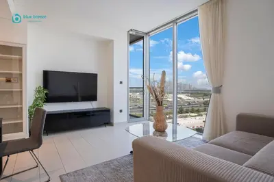 a living room with a tv and a couch and a table at Blue Breeze - 2 Bedroom near Downtown, Elegant Retreat in Sobha in Dubai