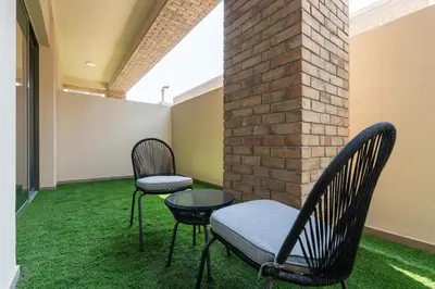 two chairs and a table in a room with grass at Ahlan HH - 1BR Haven with Study Room - Eleganz by Danube in Dubai