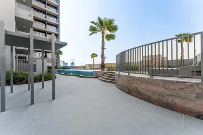 a walkway next to a building with palm trees at 1BDR with Gym, Sauna, Pool - Opposite Circle Mall in Dubai
