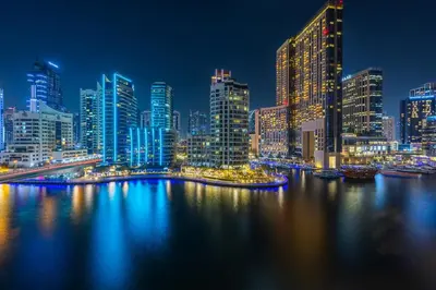 a night view of a city with a river and buildings at ShoresInn -Waterfront Bliss in Dubai Marina in Dubai