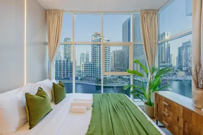 a bedroom with a large window and a large bed with green sheets at ShoresInn -Waterfront Bliss in Dubai Marina in Dubai