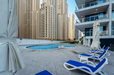 two chairs and umbrellas on a patio with a pool at ShoresInn -Waterfront Bliss in Dubai Marina in Dubai