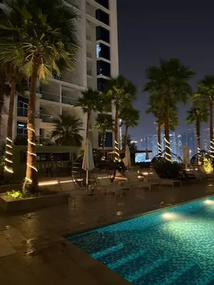a swimming pool with palm trees and a building at Elegant Urban Escape in Dubai