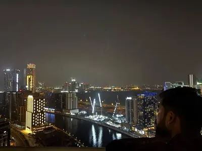 a man looking out over a city at night at Elegant Urban Escape in Dubai