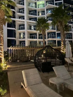 a large building with palm trees and chairs and a bird cage at Bright And Spacious Canal View Appartment in Dubai