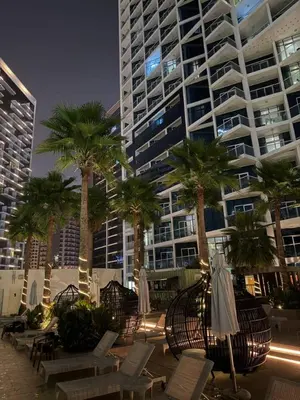 a large building with palm trees and chairs and umbrellas at Bright And Spacious Canal View Appartment in Dubai