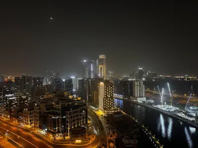 a night view of a city with a river and buildings at Bright And Spacious Canal View Appartment in Dubai