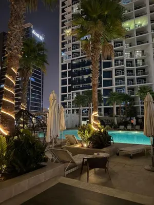 a pool with umbrellas and palm trees and buildings at Studio With Canal View in Dubai