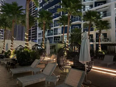 a patio with chairs and an umbrella and palm trees at Bay Luxe Studio in Dubai