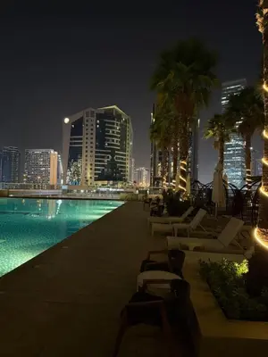 a swimming pool with a city skyline at night at Bay Luxe Studio in Dubai