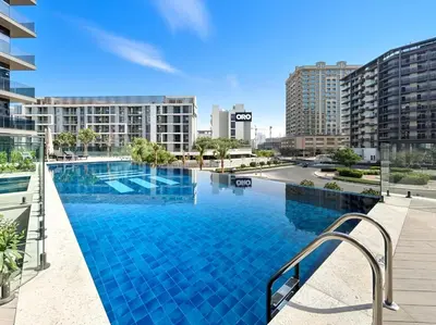 a large swimming pool with blue tiles on a building at Stylish 1BR with PS5, Sauna and Kids' Play Area in Dubai