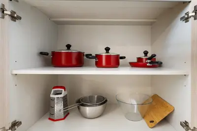 two pots and pans on a shelf in a kitchen at Stylish 1BR with PS5, Sauna and Kids' Play Area in Dubai