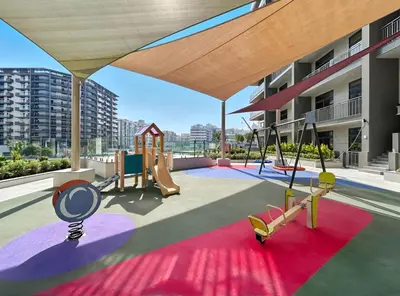 a playground in a building with a slide and swings at Stylish 1BR with PS5, Sauna and Kids' Play Area in Dubai