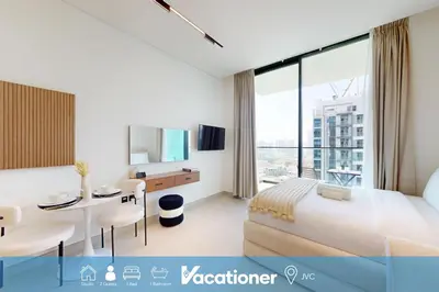 a hotel room with a bed and a desk and a table at Vacationer l Bright, Modern Studio Retreat l Free Gym, Pool Access in Dubai