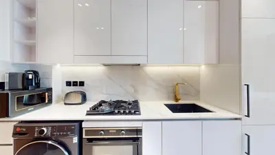 a kitchen with white cabinets and a stove top oven at Vacationer l Bright, Modern Studio Retreat l Free Gym, Pool Access in Dubai