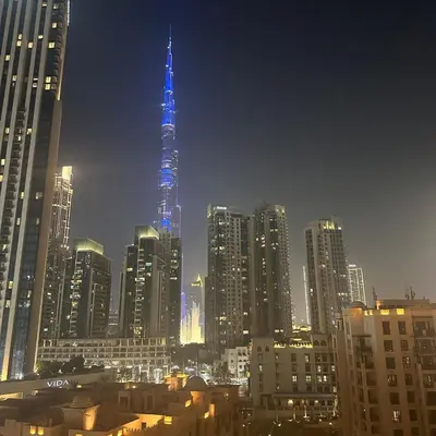 a view of a city at night with a blue tower at IMPERIAL AVENUE Brand New Ultra Luxury Full Downtown, Old Town & Burj Khalifa Amazing View! Unforgettable Stay! in Dubai