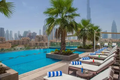 a pool with lounge chairs and palm trees on a building at Maison Privee - Dazzling Downtown Retreat with Panoramic City Views in Dubai