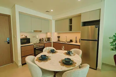 a kitchen with a table and chairs and a refrigerator at Luxury Stay - Dubai Creek Harbour - Branded Living - Burj View in Dubai