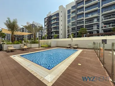 a swimming pool in front of a tall building at Newly Listed Airy Boho Studio Azizi Riviera 26 in Dubai
