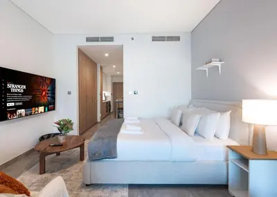 a bedroom with a large white bed and a tv at Brand New Studio for 4 Guests - Near Dubai Mall in Dubai