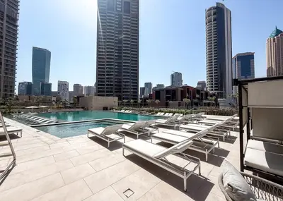 a pool with lounge chairs and a city skyline at Brand New Studio for 4 Guests - Near Dubai Mall in Dubai