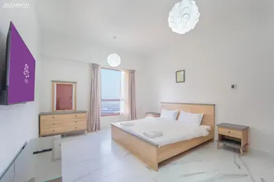 a bedroom with a bed and a tv and a window at 4BR Spacious Apartment in Sadaf 8 JBR, 3 Min Walk To The Beach With Sea and Dubai Marina View in Dubai