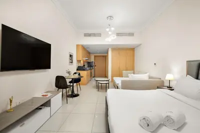 a hotel room with two beds and a flat screen tv at FIRST CLASS High End Studio near Miracle Garden in Dubai