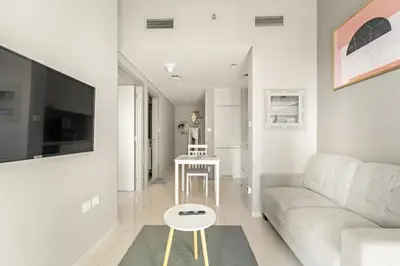 a white living room with a couch and a table at Stylish 1BR w/ Pool View | Heart of Business Bay in Dubai