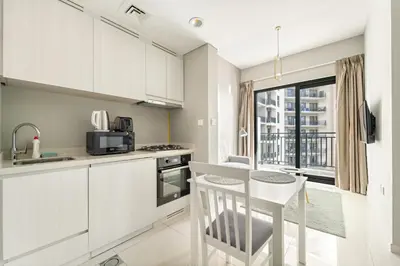 a kitchen with white cabinets and a table with a stool at Stylish 1BR w/ Pool View | Heart of Business Bay in Dubai
