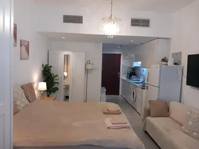 a bedroom with a bed and a couch and a kitchen at Dubai Marina Apartment in Dubai