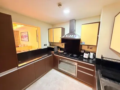 a kitchen with brown cabinets and a stove top oven at Elegant 2BR Beach Apartment Grandeur Residence, Palm Jumeirah in Dubai