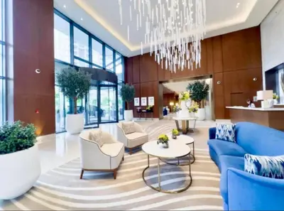 a lobby with a blue couch and chairs and a chandelier at Address Dubai Opera Residence with Burj Khalifa Views in Dubai