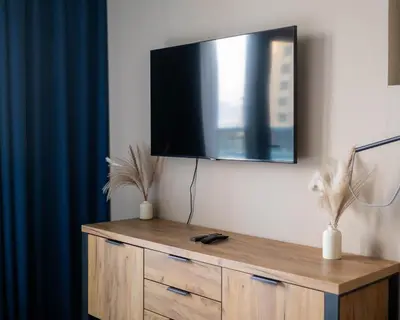 a flat screen tv on a wall with a wooden dresser at Chic Studio with Beach & Rooftop Pool Access in Dubai
