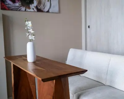 a vase of flowers on a wooden table next to a chair at Chic Studio with Beach & Rooftop Pool Access in Dubai