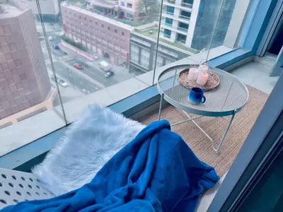 a table with a candle and a blanket on a window at COZY 1BD in Dubai Marina in Dubai