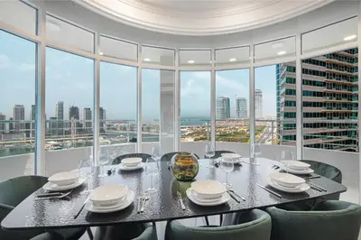 a dining room with a table and chairs and windows at Amazing Palm View - Prime Location - Spacious in Dubai