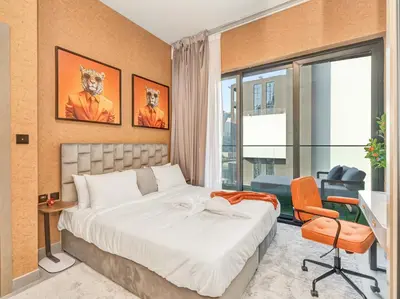 a bedroom with a bed and a desk and a window at Binghatti Canal 2 Bedroom Suite with Burj Khalifa View, Spacious Balcony, and Infinity Pool in Dubai
