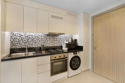 a kitchen with a stove and a sink and a washing machine at Aykon Tower - Studio Apartment - Allsopp & Allsopp in Dubai