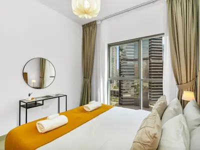 a bedroom with a large white bed and a window at Downtown 1BR Pool with Burj Khalifa View Near Dubai Mall in Dubai