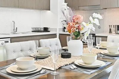a dining room table with chairs and a vase of flowers at 28th Floor Apartment Next to Burj And Mall Sleeps 7 in Dubai