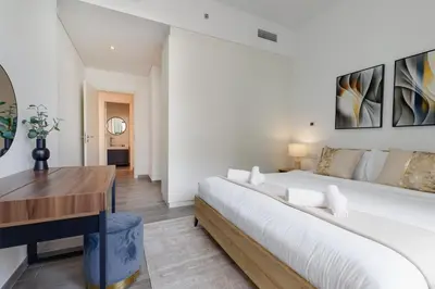 a white bedroom with a large bed and a desk at Belgravia Square, JVC - 1 Bedroom Apartment - Allsopp & Allsopp in Dubai