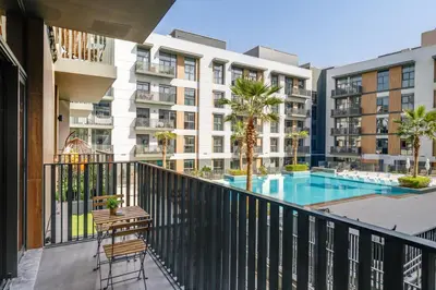 an apartment balcony with a pool and buildings at Belgravia Square, JVC - 1 Bedroom Apartment - Allsopp & Allsopp in Dubai