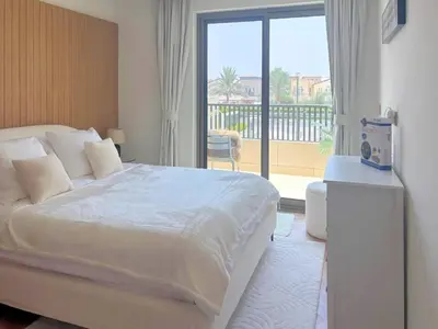 a bedroom with a large bed and a balcony at Luxury 3BR Villa with Pool View & Modern Comfort in Dubai