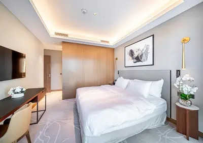a bedroom with a large white bed and a desk at Luxury 2BR at Address Opera with Burj Khalifa View in Dubai