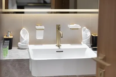 a bathroom with a white sink with a gold faucet at Trillionaire Studio, Canal Views, Private Jacuzzi in Dubai