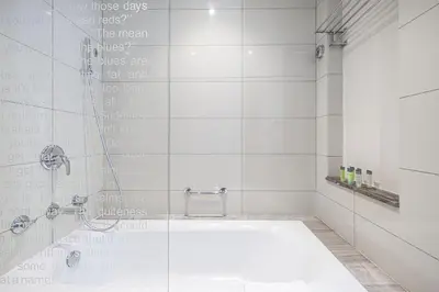 a bathroom with a tub and a shower with writing on the wall at Paramount Luxe Suite, Business Bay in Dubai
